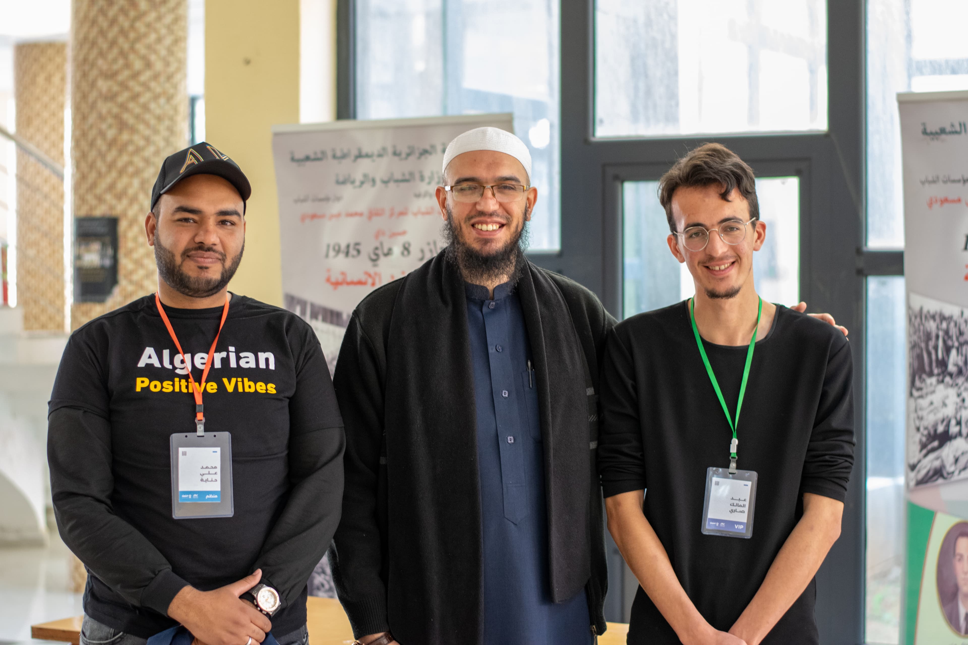 ثلاثة شباب متطوعين يبتسمون للكاميرا